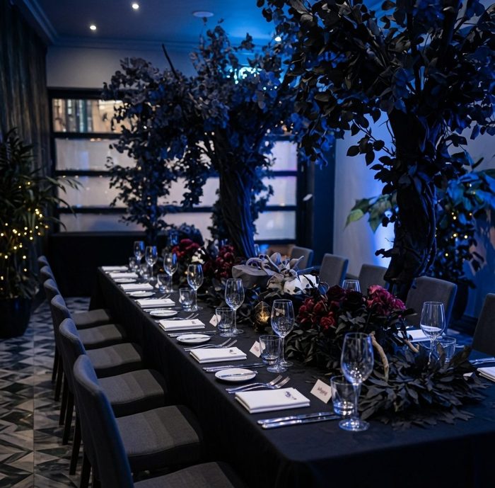 A candlelit dinner table in the Haunted Forest, dressed with black roses and dark foliage