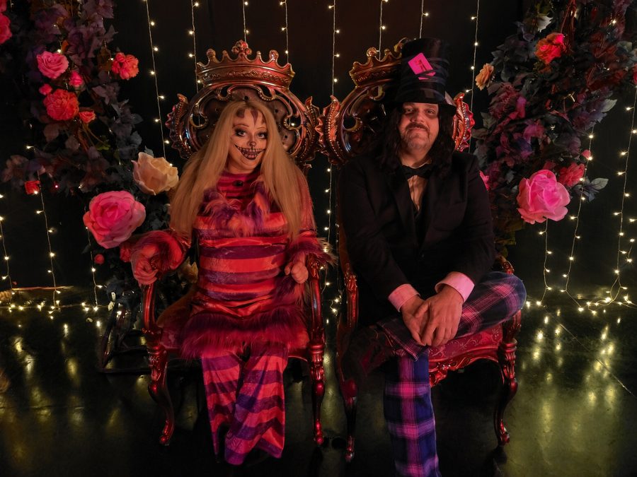 A Cheshire Cat and a Mad Hatter seated on ornate gilded thrones amid roses and fairy lights at Underland